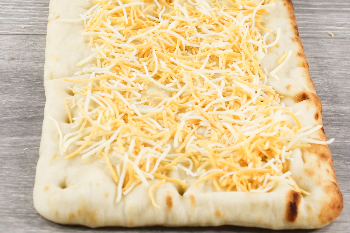 adding cheese to flatbread