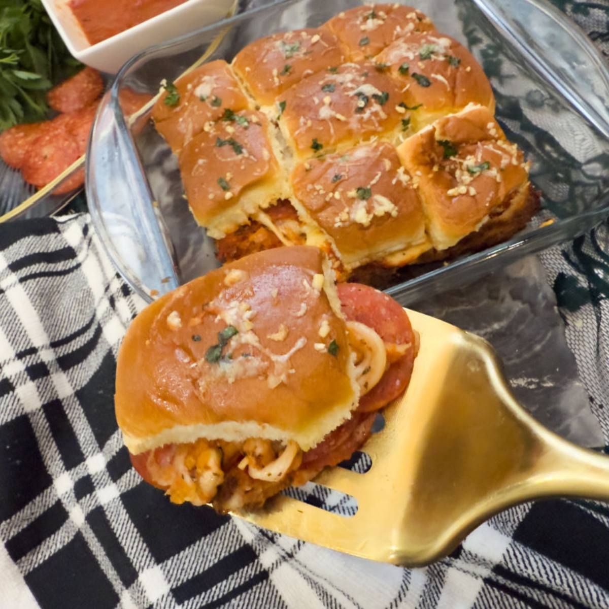 Pizza Sliders on Hawaiian Rolls with gold spatula in pan