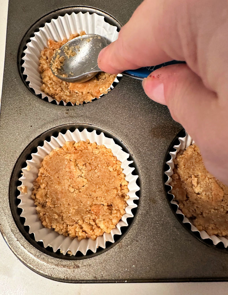 pressing graham crackers into muffin tin